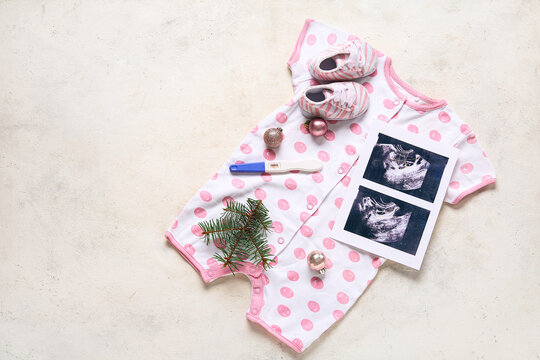 Composition with baby clothes, sonogram image and Christmas balls on light background