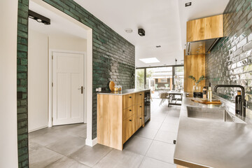 a kitchen and dining area in a house with green tiles on the walls, white doors and grey flooring
