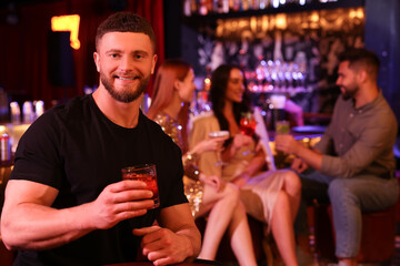 Friends spending time together in bar. Handsome man with fresh alcoholic cocktail, space for text