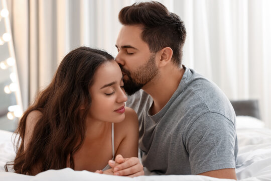 Man kissing his girlfriend on bed indoors