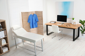 Modern medical office with doctor's workplace and examination table in clinic