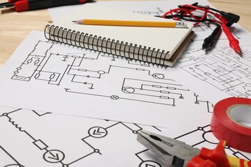 Wiring diagrams, tools and office stationery on wooden table, closeup