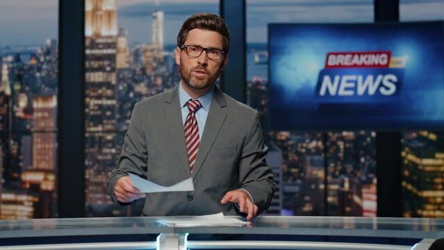 Bearded newscaster ending program in evening newsroom studio. Late breaking news