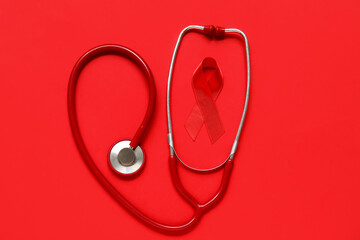 Red ribbon with stethoscope on color background. AIDS Day concept