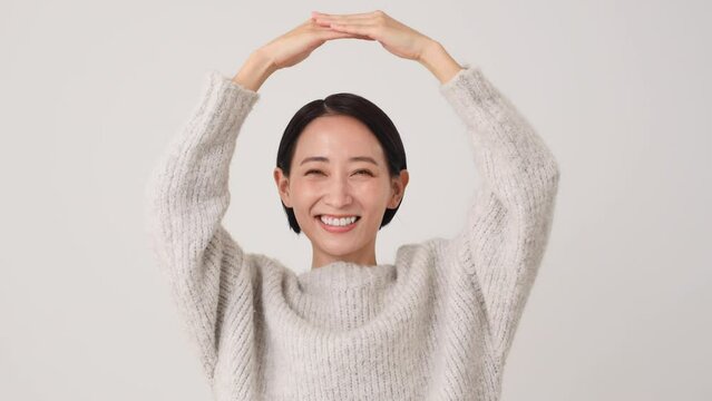 腕で丸印のジェスチャーをする中年女性　白背景