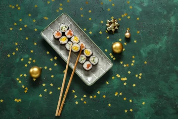 Zelfklevend Fotobehang Plate with tasty sushi rolls and Christmas decor on green background © Pixel-Shot