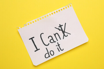 Motivation concept. Changing phrase from I Can't Do It into I Can Do It by crossing out letter T on yellow background, top view
