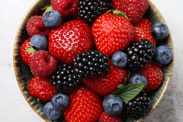 Obraz premium Different fresh ripe berries in bowl on table, top view
