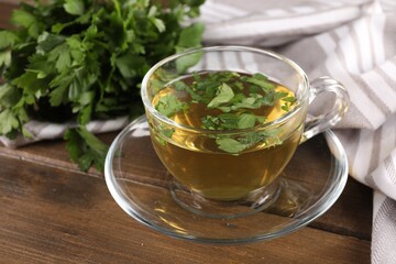 Aromatic herbal tea with parsley on wooden table, closeup