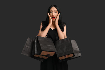 Beautiful shocked woman with shopping bags on dark background. Black Friday Sale