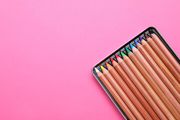 Box with many colorful pastel pencils on pink background, top view and space for text. Drawing supplies