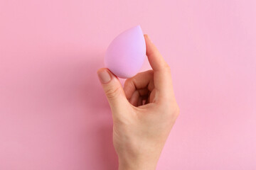 Woman with makeup sponge on pink background, top view