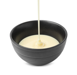 Pouring condensed milk into bowl isolated on white