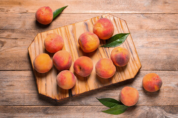 Fresh peaches and leaves on wooden table, flat lay