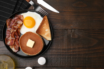 Tasty pancakes served with fried egg and bacon on wooden table, flat lay. Space for text