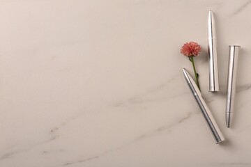 Bullets and beautiful flower on light marble table, flat lay. Space for text