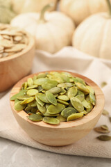 Wooden bowl with pumpkin seeds on table
