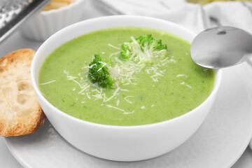 Delicious broccoli cream soup with cheese on white table, closeup