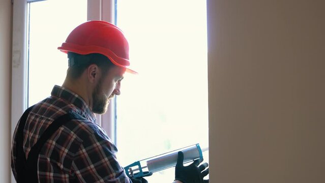 A worker is applying polyurethane foam to fill gap between sash and window frame