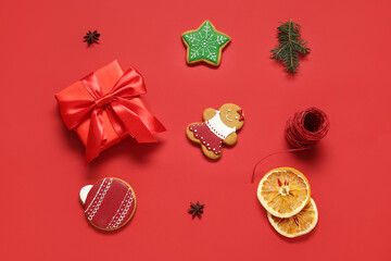 Tasty Christmas cookies with gift box and decor on red background