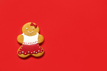 Tasty Christmas cookie in shape of girl on red background