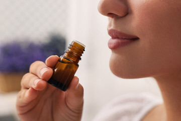 Woman with bottle of essential oil indoors, closeup - obrazy, fototapety, plakaty