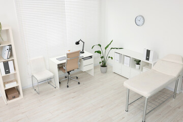 Modern medical office with doctor's workplace and examination table in clinic