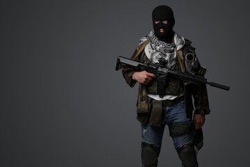A Middle Eastern radical soldier dressed in a black balaclava and camouflaged field uniform, armed...