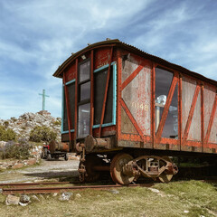 Fototapeta na wymiar Tren abandonado transformado en casa de color marron y madera en via de tren