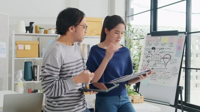 Two young Asian startup company partners disagreeing opinions argue in small business office, disappointed profit marketing plan jobs, and freelance work as E-commerce entrepreneur and coworker team.