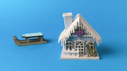 A house in New Year's style and a wooden sleigh on a blue background.