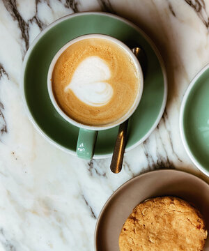 Taza de cafe con forma de corazon acompa&ntilde;ado con una galleta en el desayuno