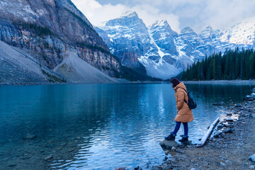 Female tourist carries a backpack, travels, walks, admires the beauty of the reflection in the...