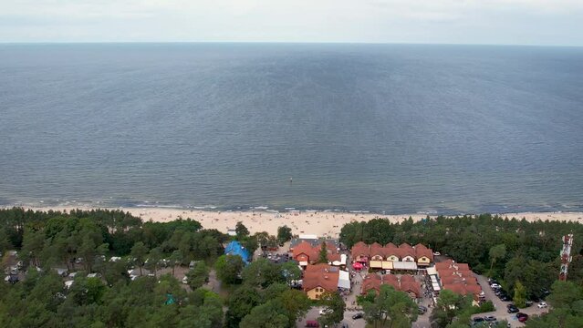 Aerial shot of a coastal area with a sandy beach in Stegna, blue waters, and a bordering tree line.