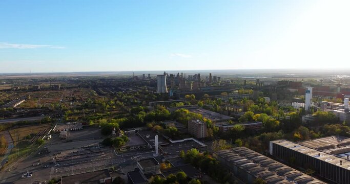 Aerial wide shot showing a time-worn industrial area and multipole towering smokestacks, clear sunny day, with blue sky 4K50fps