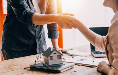 Real estate broker agent presenting and consult to customer to decision making sign insurance form agreement, buy and sell home model, concerning mortgage loan offer for and house insurance