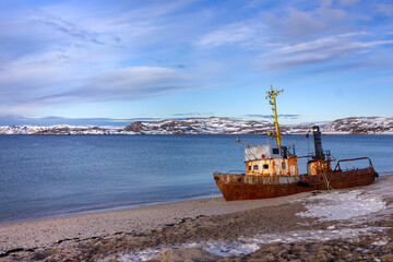 An old rusty fishing boat washed ashore in the Barents Sea of the Arctic Ocean in Teriberka close-up