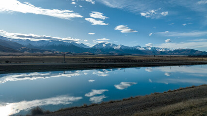 Obraz premium Aerial view of the Pukaki hydro power scheme canal in rural Twizel running in parallel with the now capped Ben Ohau mountain range