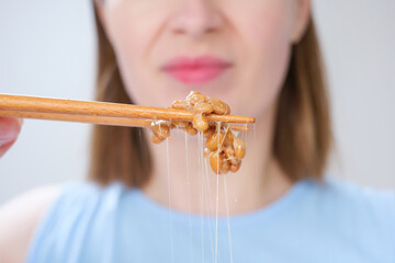 Young woman holding wooden sticks with Japanese fermented natto beans front view close-up,...
