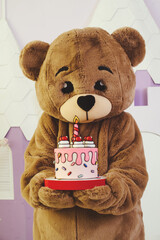 bear costume with a festive cake in his hands