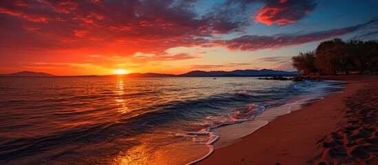 The orange sunset cast a vibrant red hue over the tranquil beach as the light from the sun...