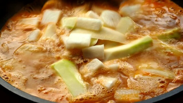 Cooking tamarind sour soup with papaya or Kang som , Thai famous food.