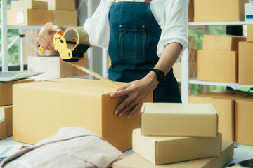 Online entrepreneur using scotch tape to seal parcel box.