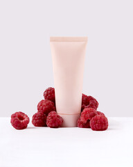 tube with cream surrounded by raspberries. The concept of natural cosmetics, body and face care