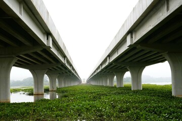 Photo taken from below two large bridges crossing the river in beautiful parallel lines on a...
