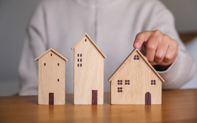 Closeup image of a woman pointing finger at a wooden house models