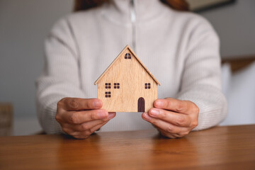 Closeup image of a woman holding and showing a wooden house models