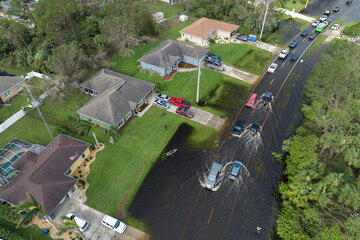 Hurricane flooded street with moving cars and surrounded with water houses in Florida residential...