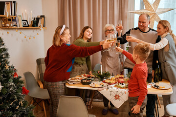 Christmas family dinner with relatives of different ages and genders, drinking champagne, Christmas décor, holiday table, celebrating the new year with the family 