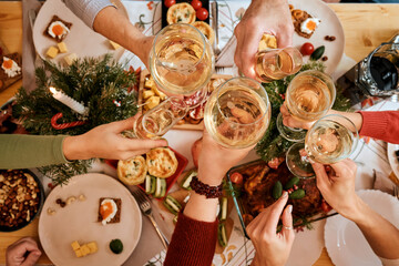top view of a Christmas New Year's Eve decorated table,  five non-personalized people eating at the table, passing dishes to each other